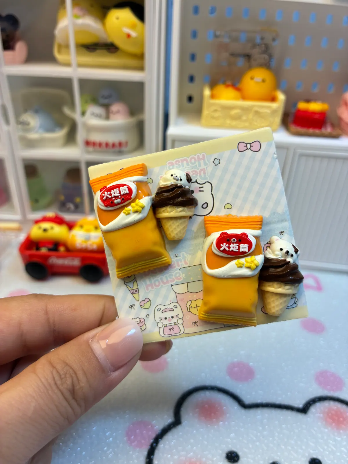 台紙に置かれたスナック袋2点とアイスクリーム2点の手作りシリコンミニチュア